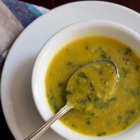 methi dal served in a white bowl with a spoon.