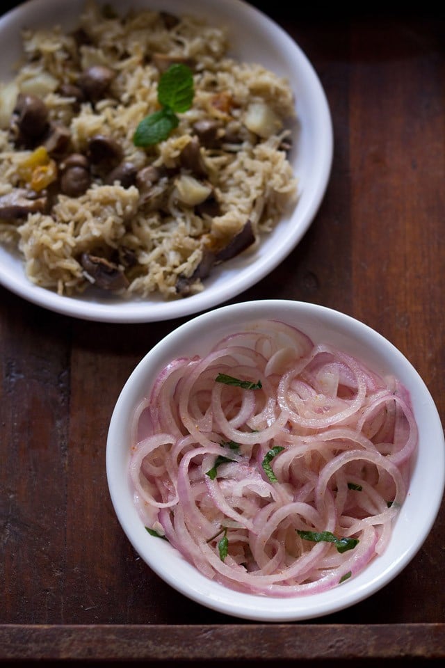 onion salad served in a white bowl with a pulao plate kept on the upper left side. 