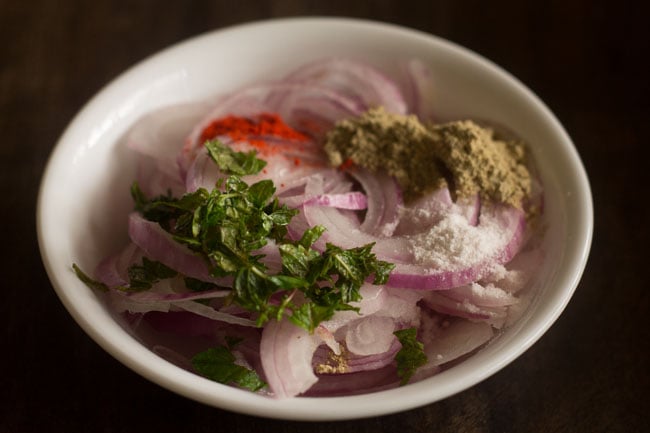 onions rings, red chili powder, chaat masala, chopped mint leaves and salt added to a bowl. 