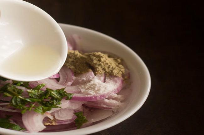 adding lemon juice to the spiced onion rings in the bowl. 