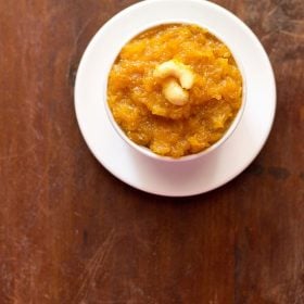 papaya halwa garnished with cashews and served in a white bowl kept on a white plate.