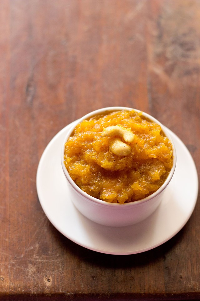 papaya halwa served in a white bowl kept on a white plate. 