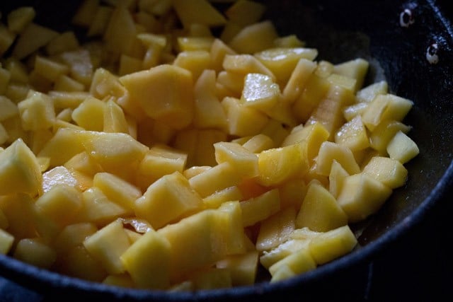 chopped semi ripe papaya in hot oil in a pan.
