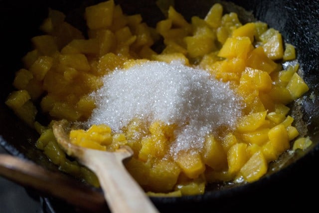 sugar added to chopped papayas cooking in the pan. 