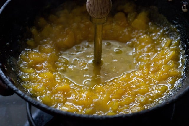 mashing chopped papaya with a potato masher. 