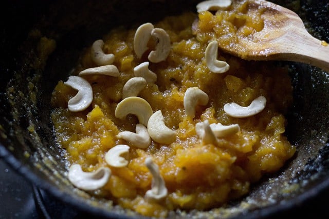 halved cashews added to papaya halwa in the pan. 