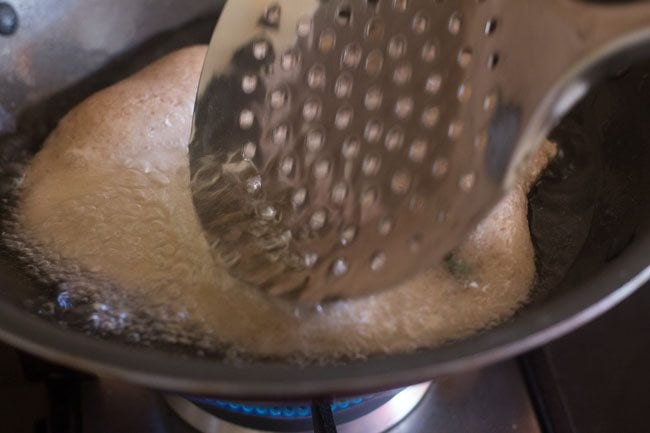 nudging singhare ki poori with a slotted spoon