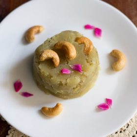 sweet potato halwa garnished with fried cashews, rose petals and served on a white colored plate.