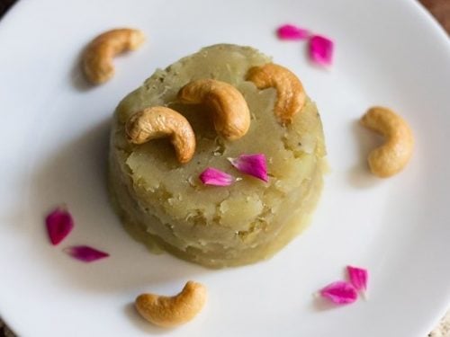 sweet potato halwa garnished with fried cashews, rose petals and served on a white colored plate.