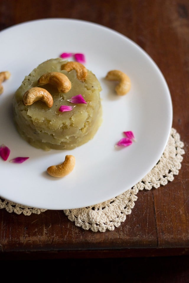 sweet potato halwa garnished with fried cashews, rose petals and served on a white colored plate.