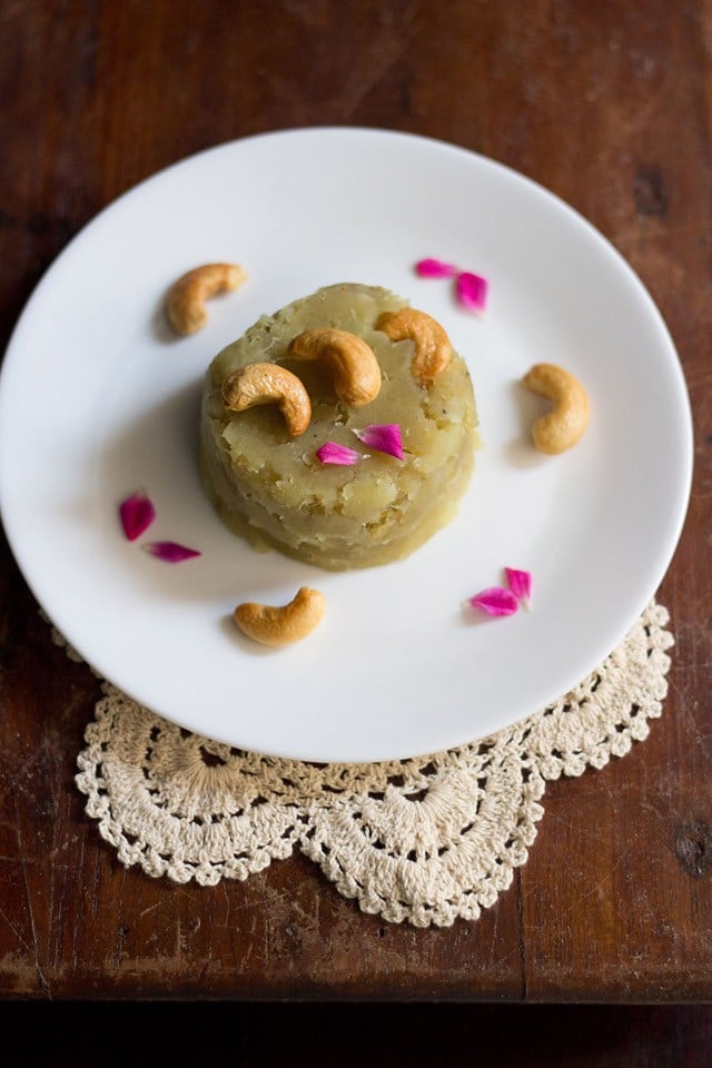 sweet potato halwa garnished with fried cashews, rose petals and served on a white colored plate.