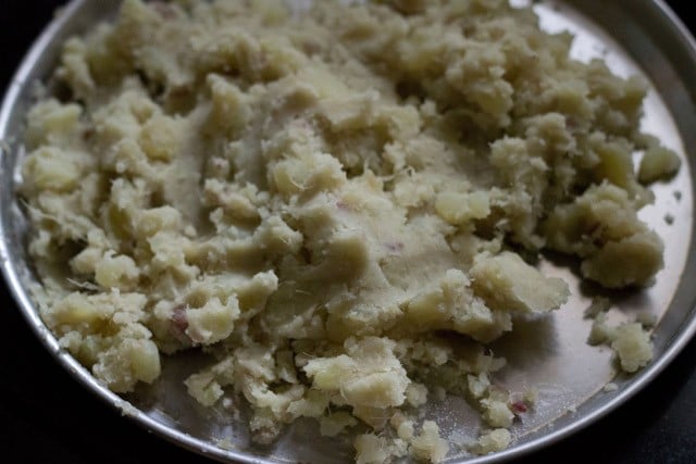 boiled, peeled and mashed sweet potatoes on a steel plate to make shakarkandi ka halwa