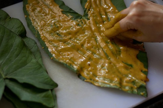 applying batter on colocasia leaves for making pathrode. 