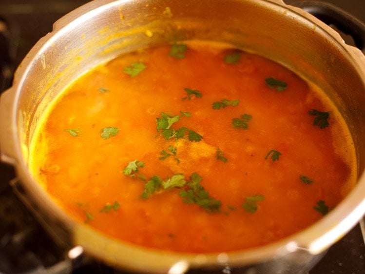 garnishing tomato dal with coriander leaves