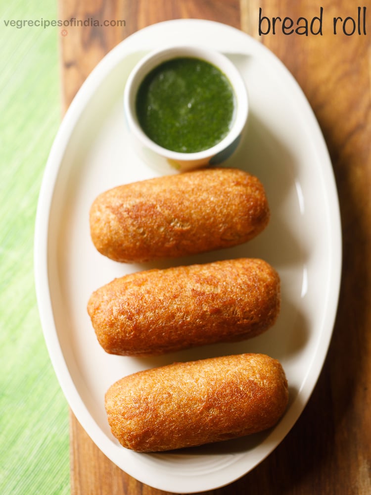 bread roll served on a white platter with a bowl of green chutney kept on the top side.