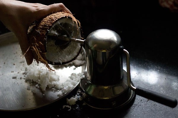 grating a coconut to get the white coconut meat for making coconut milk. 