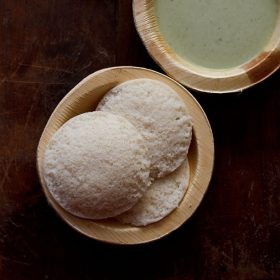 top shot of leftover rice idli served in wooden bowls with coconut chutney in one of the bowls.