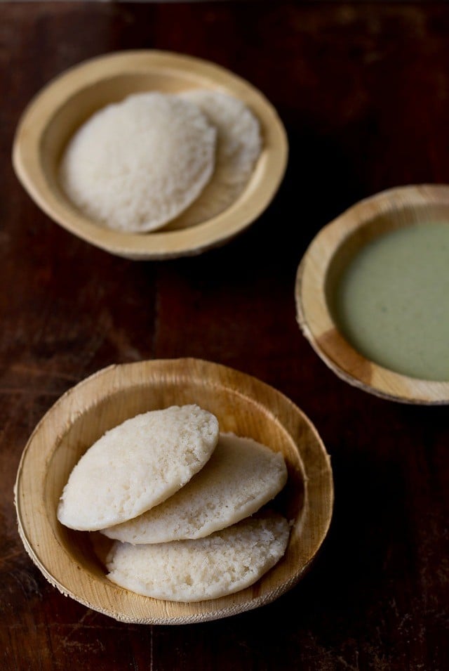 leftover rice idli served in wooden bowls with coconut chutney in one of the bowls kept on the side.