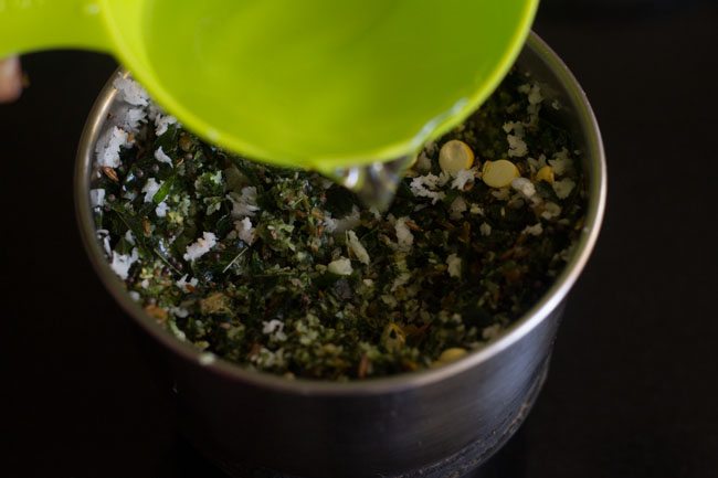 adding water to the grinder jar to make curry leaves chutney. 