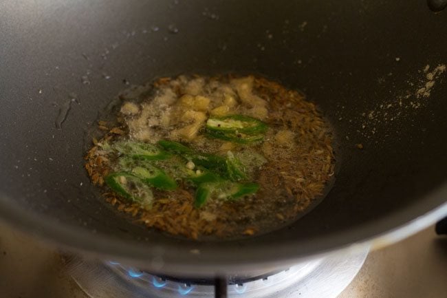 cumin seeds, chopped ginger, chopped green chilies and asafoetida added to hot oil for making kadi patta chutney. 