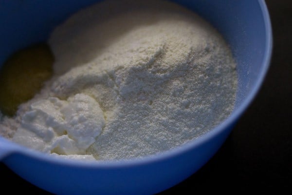 milk powder, all-purpose flour, baking soda, salt, ghee and fresh curd added in a mixing bowl.