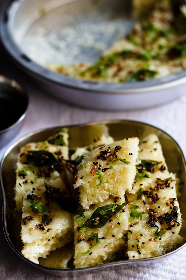 closeup shot of rava dhokla served in a steel plate