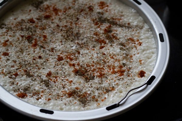batter poured in a greased steamer and sprinkled with black pepper powder, red chili powder and roasted sesame seeds. 