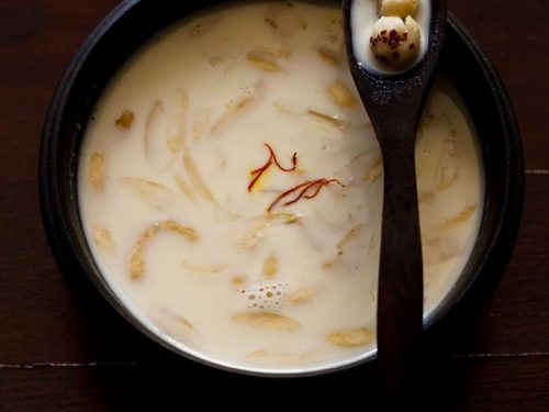 makhane ki kheer served in a black bowl with a spoon kept on it.