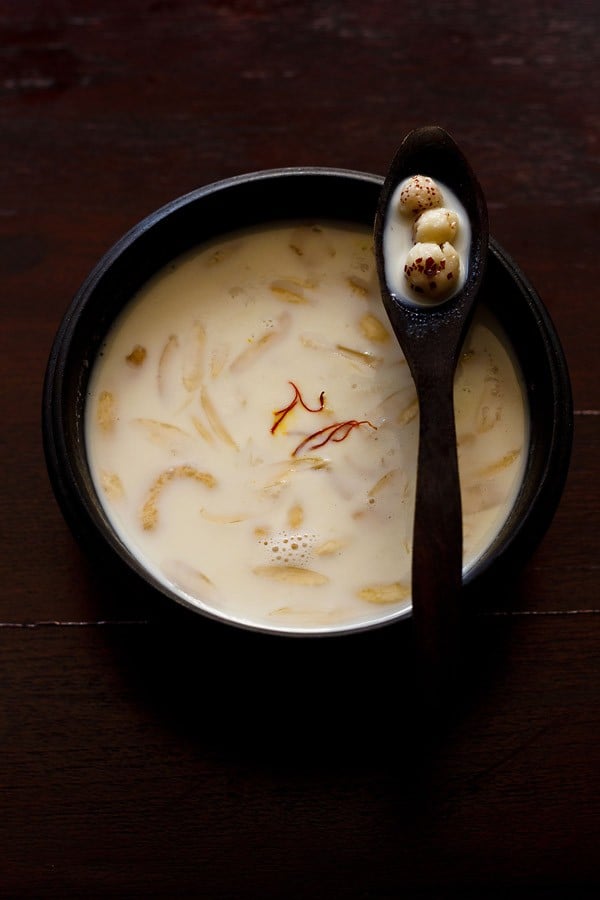 makhane ki kheer served in a black bowl with a spoon kept on it.