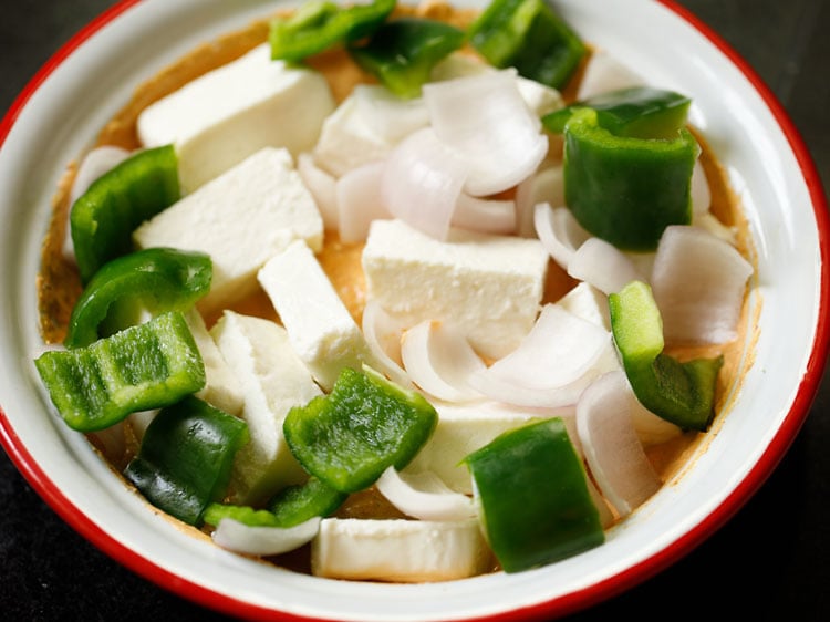 se añaden los cubos de paneer, las cebollas y el pimiento verde