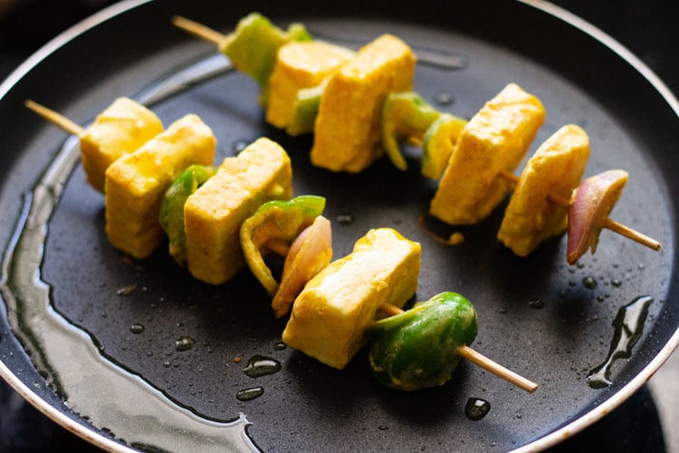 paneer tikka spiesjes die op een koekenpan worden gebakken