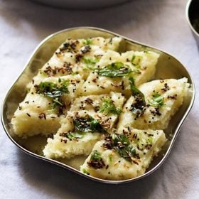 rava dhokla slices in a steel square plate.