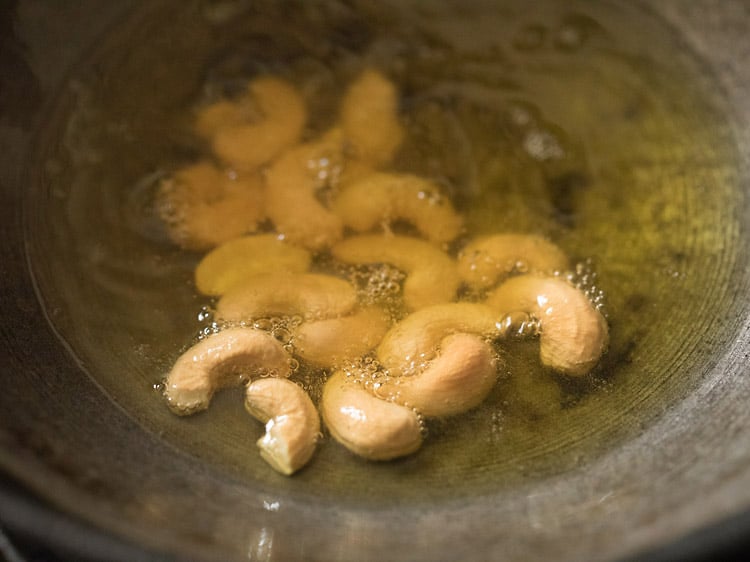 frying cashews in ghee till golden for rava kesari recipe.