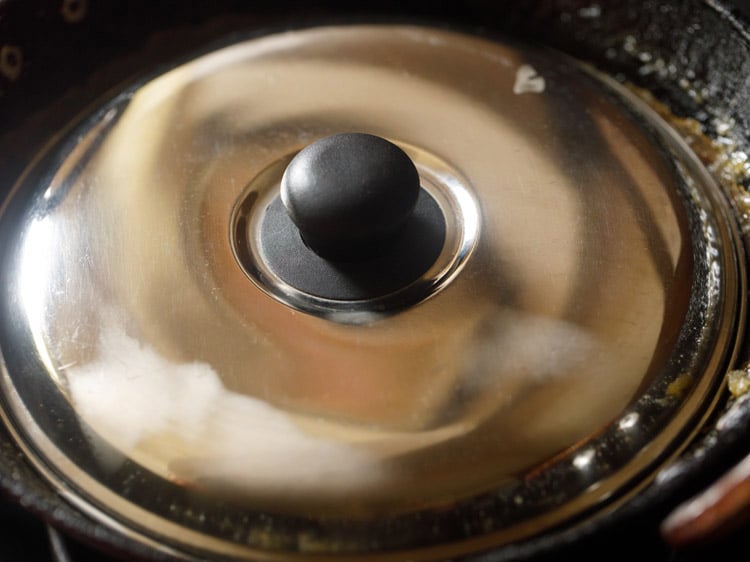 cooking kesari in the pan with a closed lid.