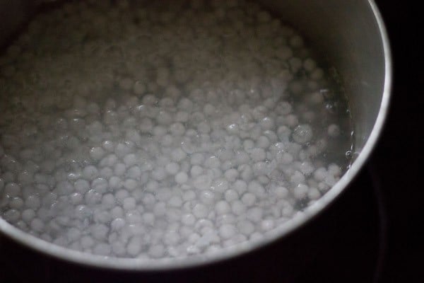 sabudana getting cooked in water in a pan. 