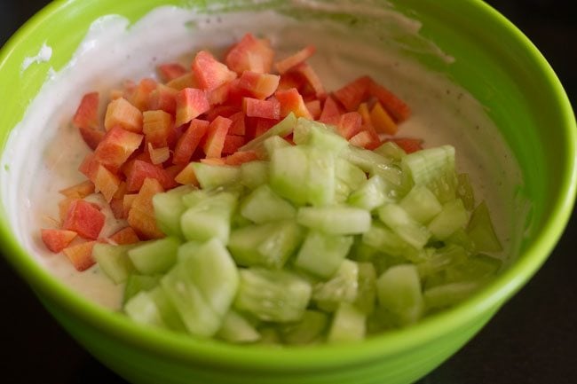 finely chopped carrot and finely chopped cucumber added to spiced curd mixture for making mix vegetable raita. 