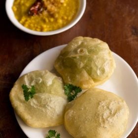 koraishutir kochuri served on a white plate with a bowl of cholar dal kept on the top left side.