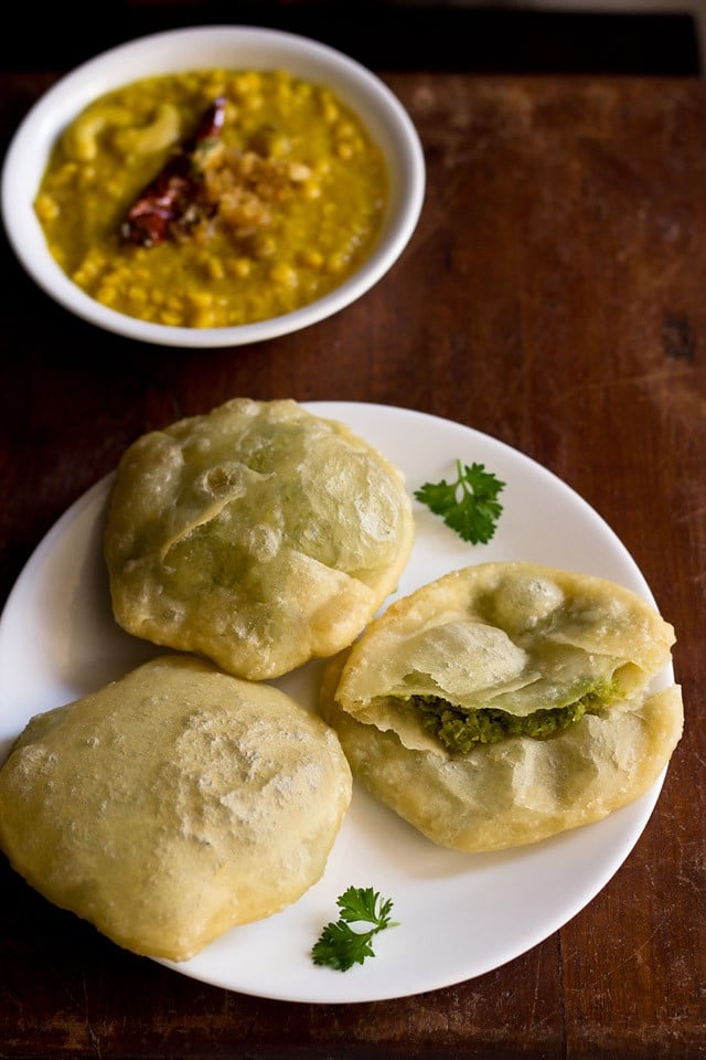 koraishutir kochuri served on a white plate with a bowl of cholar dal kept on the top left side. 