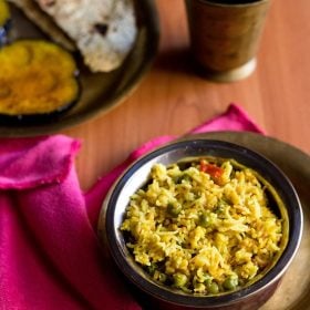 khichuri recipe served in a bowl with baingan bhaja and papad in the a plate kept in the background.