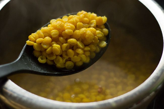 cooked chana dal in a black spoon
