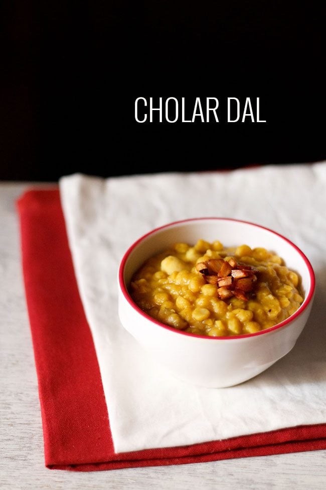 cholar dal with fried coconut bits on top in a red rimmed bowl