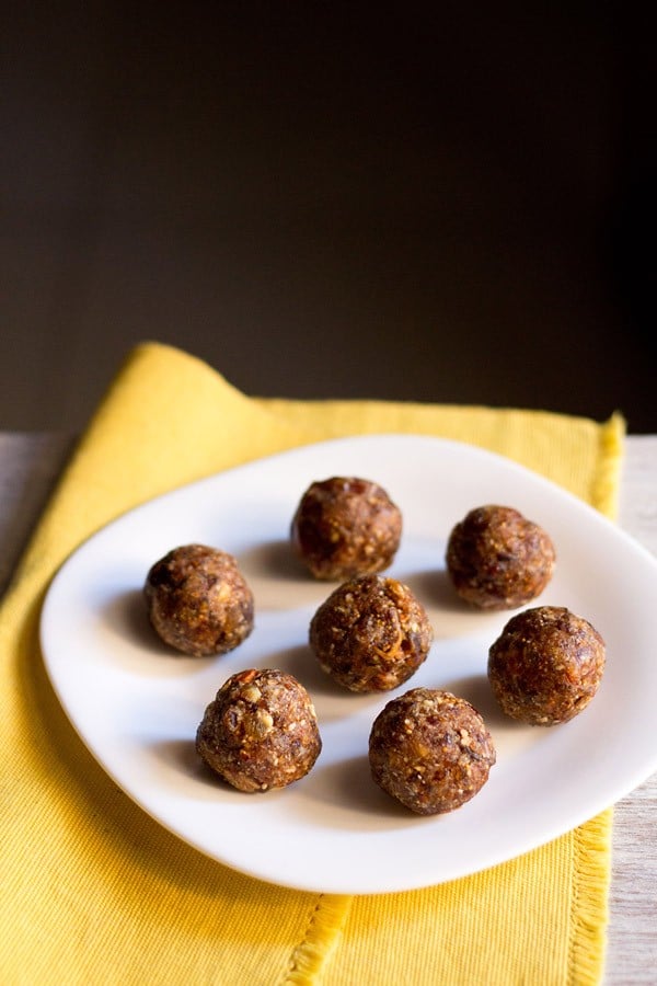 dry fruit ladoo placed on a white plate on a yellow napkin