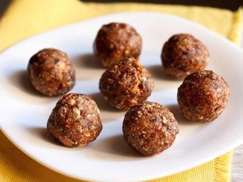 seven dry fruits ladoo placed on a white plate on a yellow napkin