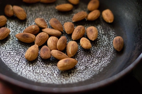 roasting almonds in a sliver-black dotted frying pan