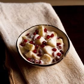 fruit raita served in a brown rimmed ceramic bowl.