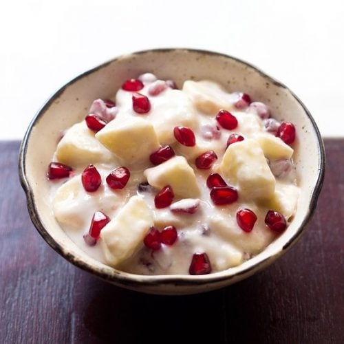 fruit raita served in a brown rimmed ceramic bowl.