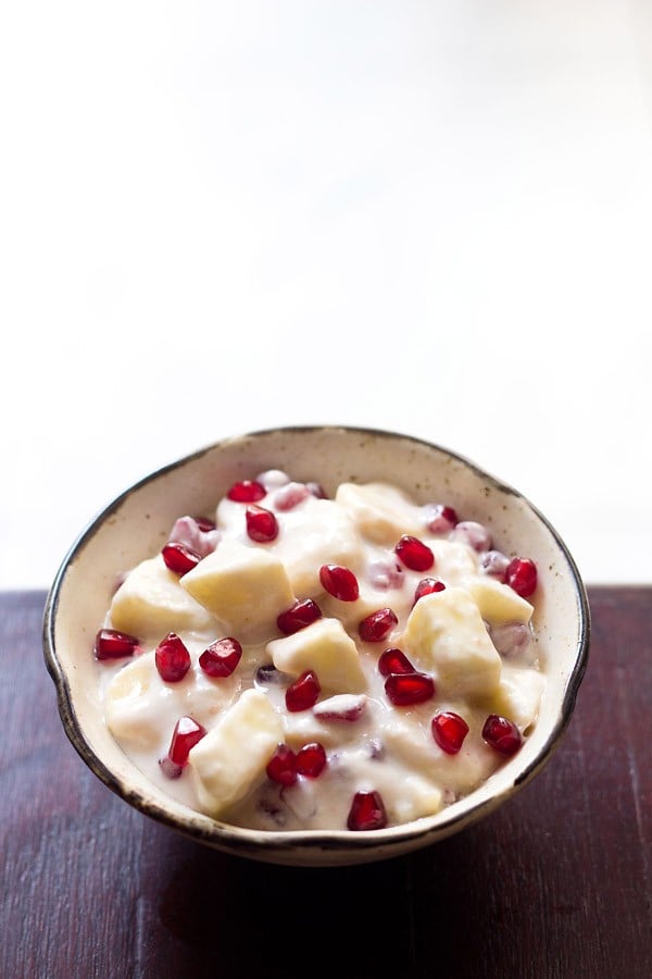 fruit raita served in a brown rimmed ceramic bowl. 