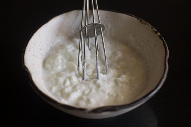 whisking the curd in a bowl. 