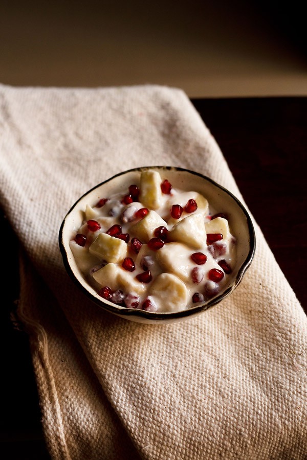 fruit raita served in a brown rimmed ceramic bowl.