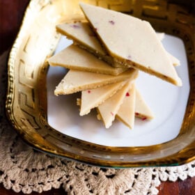 kaju katli stacked spirally on a golden rimmed white square plate